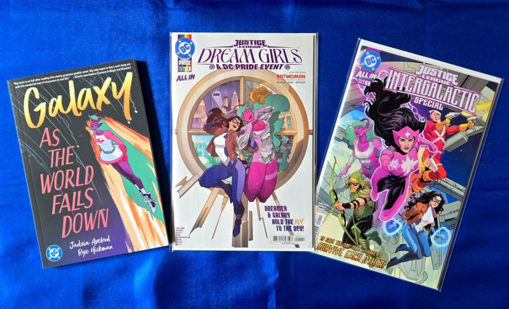 The covers of Galaxy: As the World Falls Down graphic novel (cover art by Rye Hickman), Justice League: Dream Girls - A DC Pride Event #1 (cover art by Ted Brandt and Ro Stein), and Justice League Intergalactic Special #1 (cover art by Travis Moore and Tamra Bonvillain)
